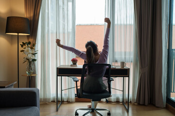 Young woman stretching at desk while working from home office