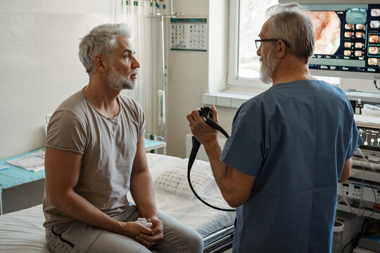 Doctor explaining colonoscopy results to patient using monitor images.