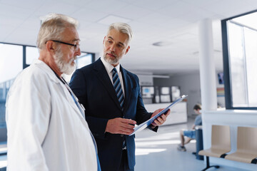 Doctor talking with hospital manager, walking down hospital hallway.