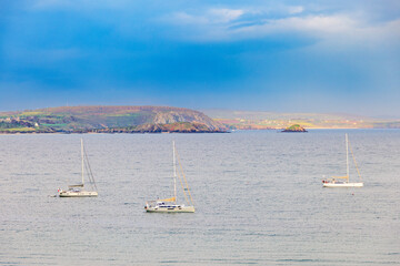 Sailboats at sea in a rocky coast in evening light
