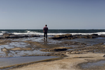 A man walks on the beach by the ocean