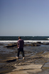 A man walks on the beach by the ocean