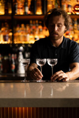 Attractive young man bartender making cocktail in a bar