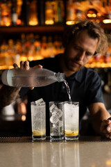 Attractive young man bartender making cocktail in a bar