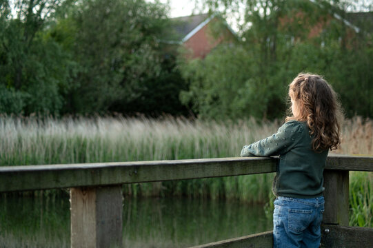 Back of girl stand in wooden bridge  and looking at the pond