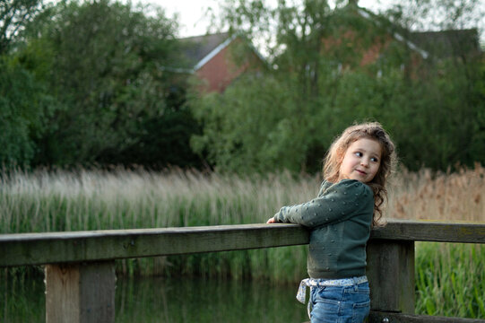 girl standing on wooden bridge  and looking back