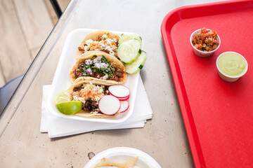 Tacos on styrofoam and tray on casual dining table