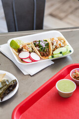 Tacos on styrofoam on metal table with tray vertical