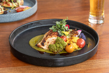 Upscale chicken dish with vegetables on wood table