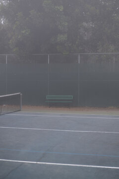single green bench at tennis court with grey fog