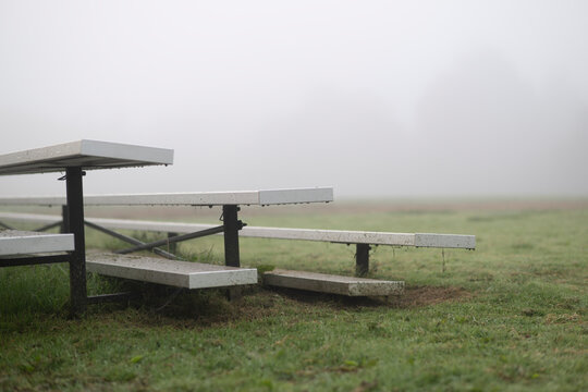 close up of metal bleachers covered in cut grass in fog