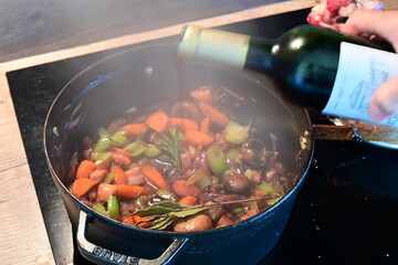 Close-Up of Deglazing Sautéed Vegetables with Red Wine in Black Pot – Home Cooking Background
