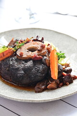 Plated serving of braised beef with bone in red wine sauce, accompanied by tender potatoes, root vegetables, and fresh herbs