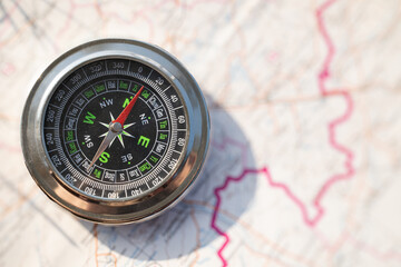 Close-up of metallic magnetic compass on paper topographic map background
