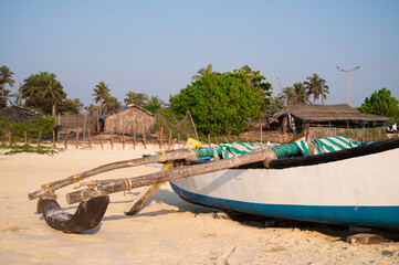 Old wooden boat on the beach in Goa, palm trees, South India, tropical west coast, Arabian Sea in Asia, vacation destination