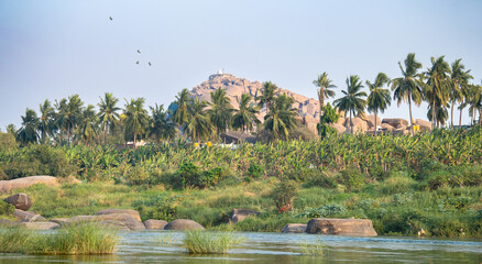 Tungabhadra river with boulders in Hampi, view to Hippie island, landscape South India, Karnataka, travel destination