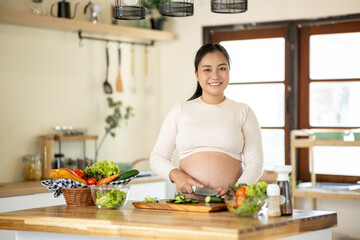 Pregnant Asian woman cooking healthy food at home