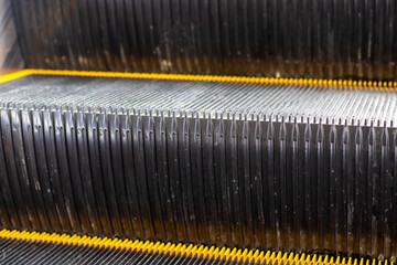 Close up of an escalators bottom section with yellow stripes