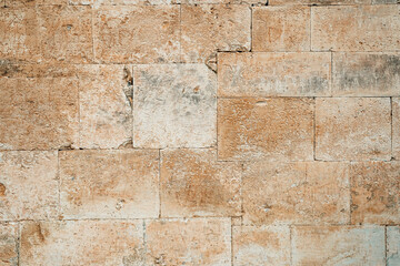 Antique ancient stone wall masonry texture background. Old wall made of beige stone blocks 