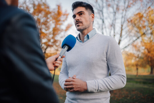Journalist interviewing politician in park during autumn