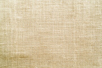 Natural beige linen fabric with a woven texture.  Close-up view showcasing the crisscrossing threads