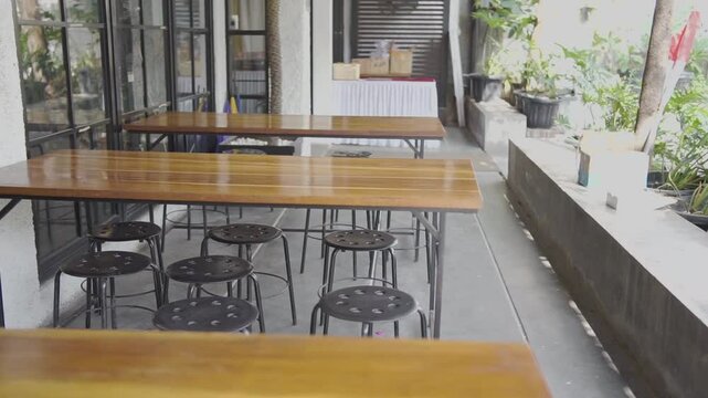 Interior wooden table and chairs in an open space with greenery