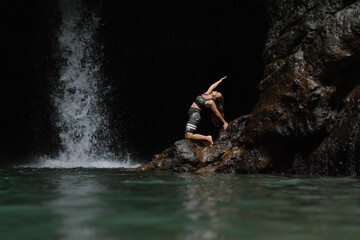 Woman practising yoga in front of waterfall on the island of Bali
