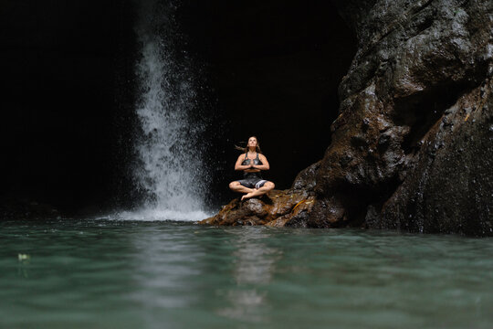 Woman practising yoga in front of waterfall on the island of Bali