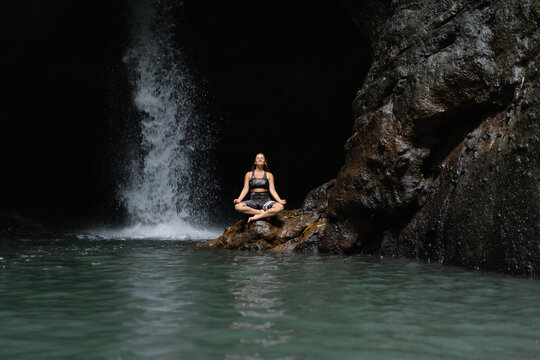 Woman practising yoga in front of waterfall on the island of Bali