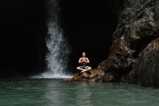 Woman practising yoga in front of waterfall on the island of Bali