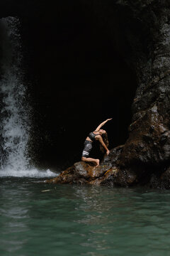 Woman practising yoga in front of waterfall on the island of Bali