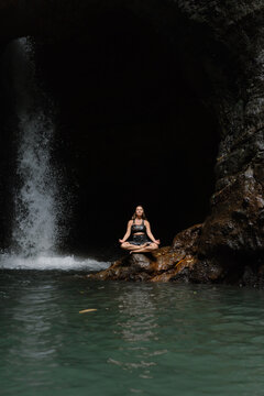 Woman practising yoga in front of waterfall on the island of Bali