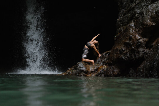 Woman practising yoga in front of waterfall on the island of Bali