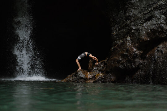 Woman practising yoga in front of waterfall on the island of Bali