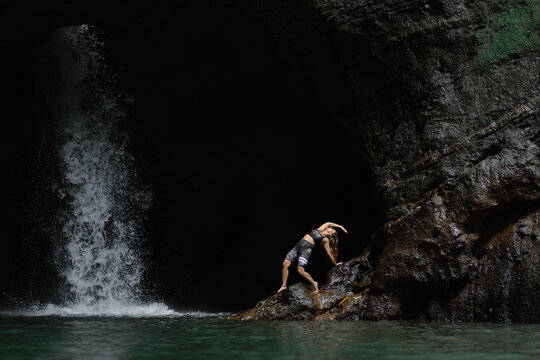 Woman practising yoga in front of waterfall on the island of Bali