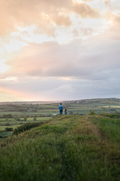 Father and daughter staying on the hill and looking at the valley.