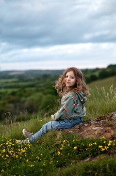 A girl sitting on slope turned around and looks at the camera.