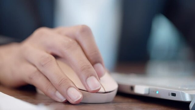 A person is using a computer mouse. The mouse is on a table. The person is wearing a suit