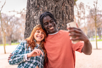 Happy multi ethnic couple taking a selfie in a park