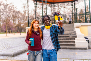 Content creators filming a vlog in a park using a smartphone and microphone