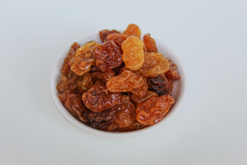 Pile of raisins in a small white bowl, isolated on white background