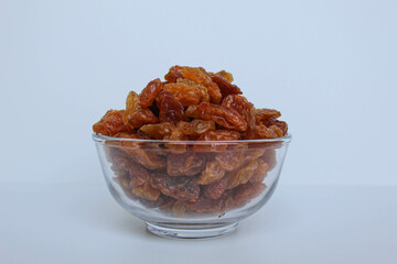 Pile of raisin in a transparent bowl, isolated on white background