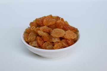 Raisins in a small white bowl, isolated on white background