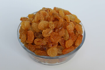 Yellow raisins in a transparent bowl, isolated on white background