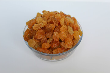 Yellow raisins in a transparent bowl, isolated on white background
