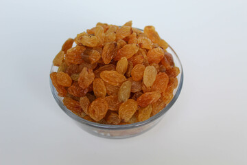 Yellow raisins in a transparent bowl, isolated on white background
