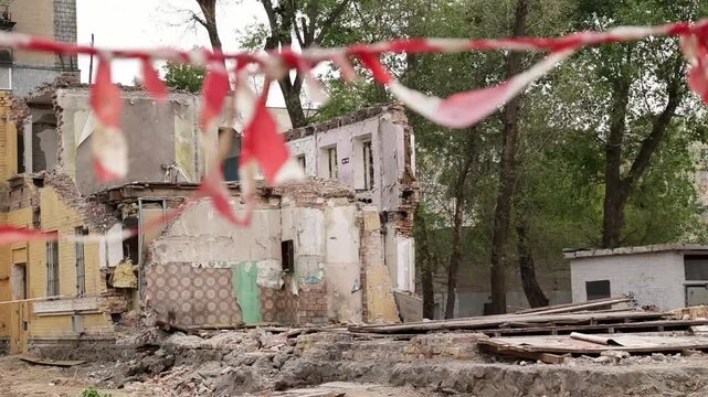 Red and white safety tape marks a construction site as we see abandoned structures and scattered debris. This place is undergoing significant changes and renovations.