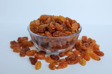 Overflow raisins from a transparent bowl, scattered, isolated white background