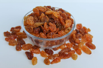Overflow raisins from a transparent bowl, scattered, isolated white background