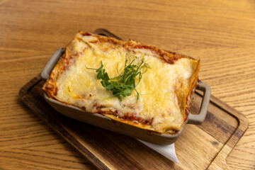 Lasagna served in a ceramic bowl on a wooden board